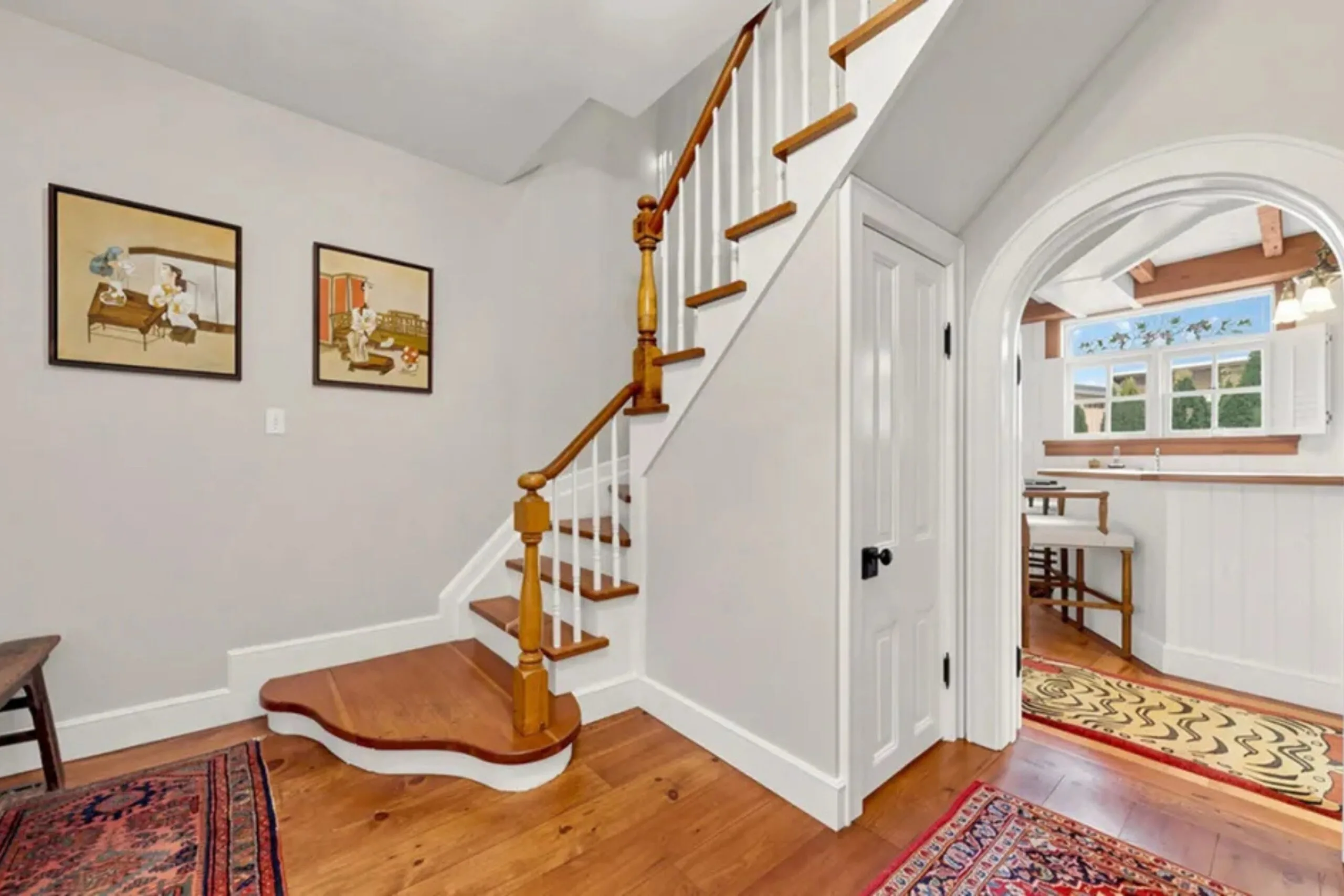 Bright entrance hall with timber floors, staircase and arched doorway leading into the kitchen.