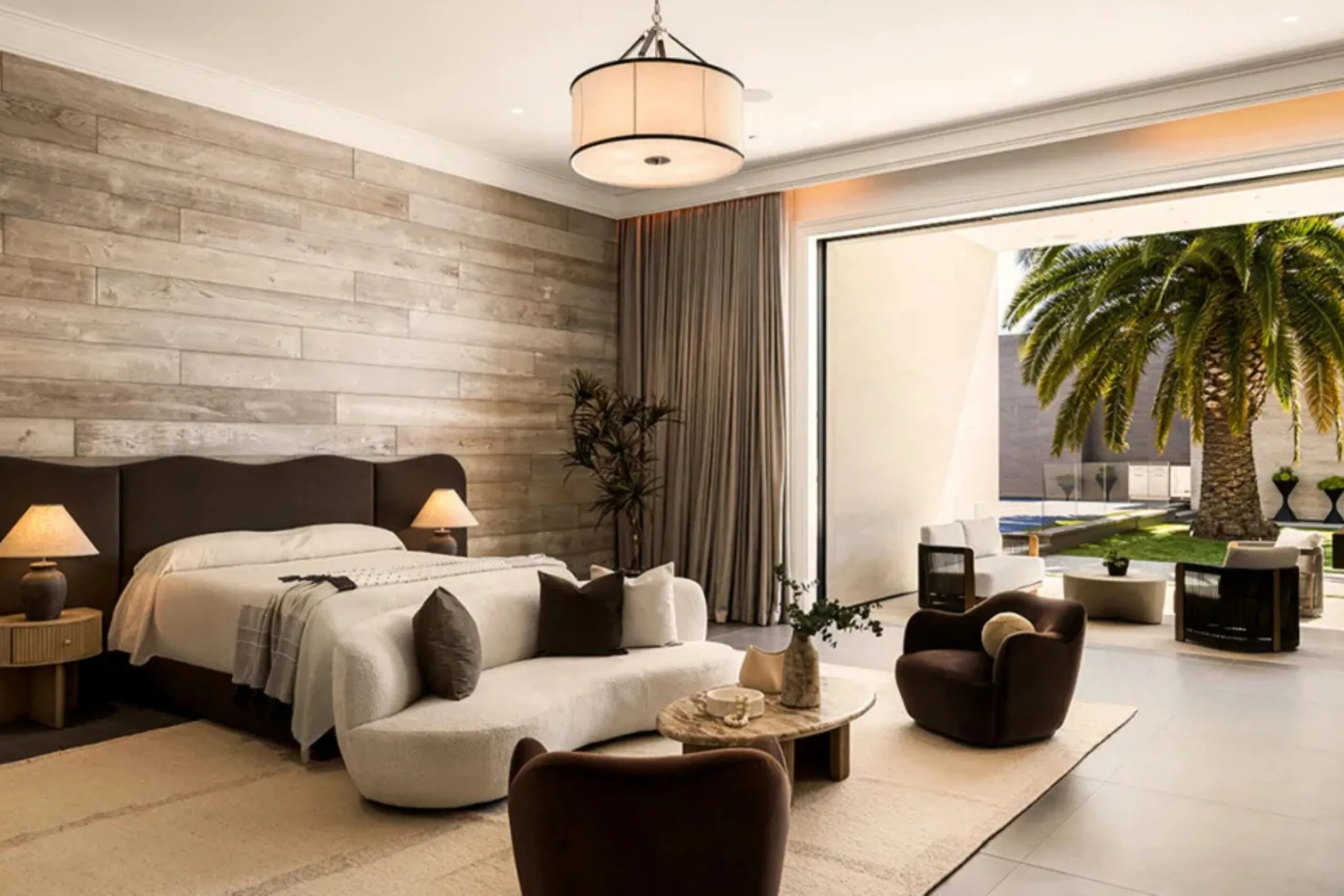 Large bedroom inside Kylie Jenner&rsquo;s Holmby Hills mansion with neutral furniture, stone walls and doors opening onto the courtyard.