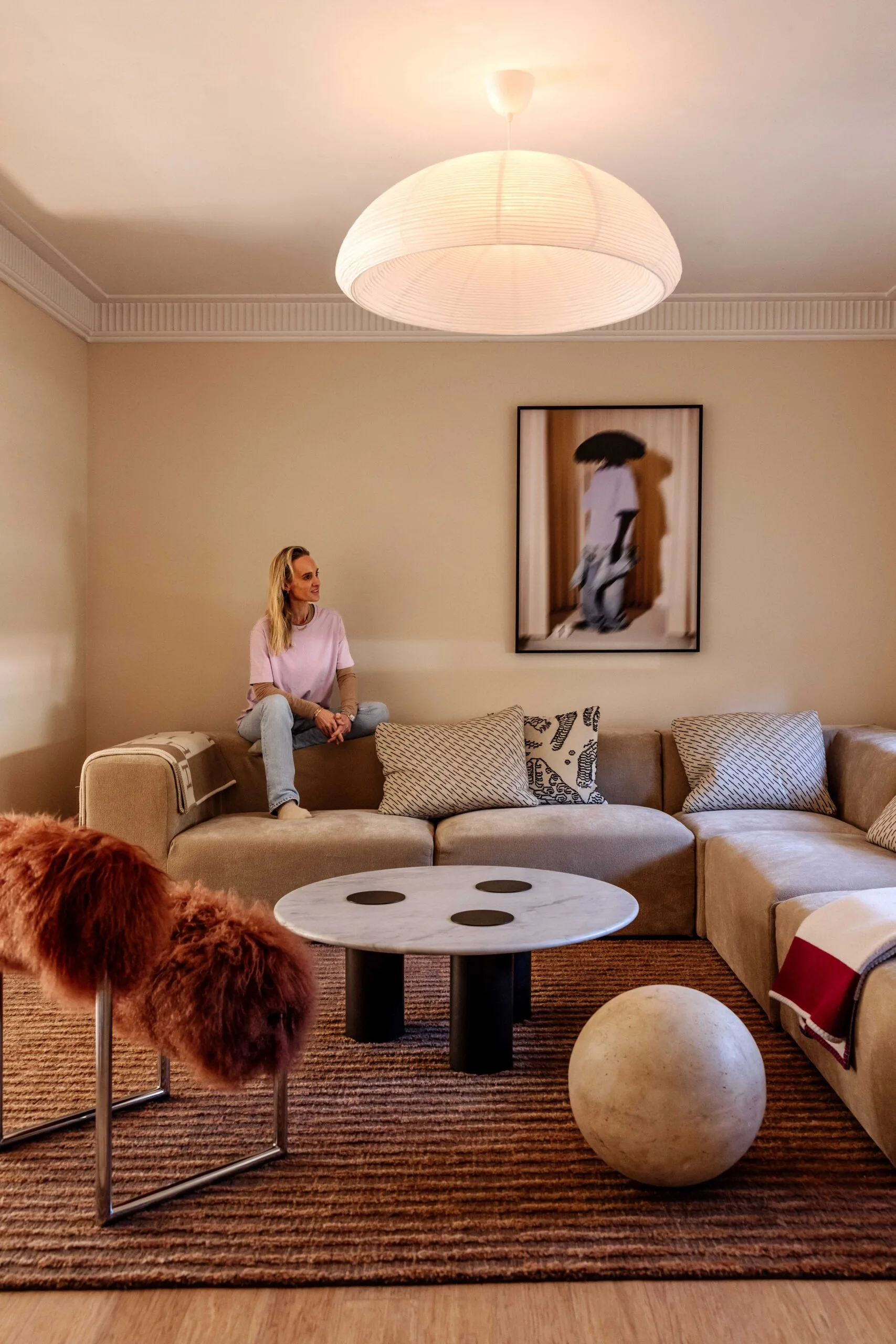 Interior designer Claudia Lambert at home in her living room with artwork and modular sofa and marble ball