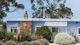 Blue weatherboard beachhouse exterior in front of ocean views
