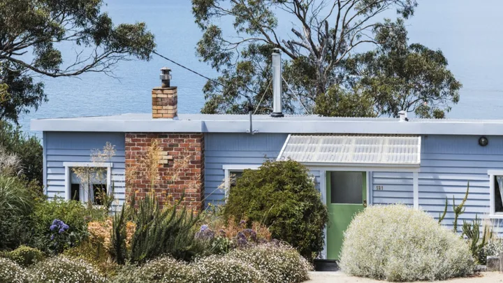 Blue weatherboard beachhouse exterior in front of ocean views