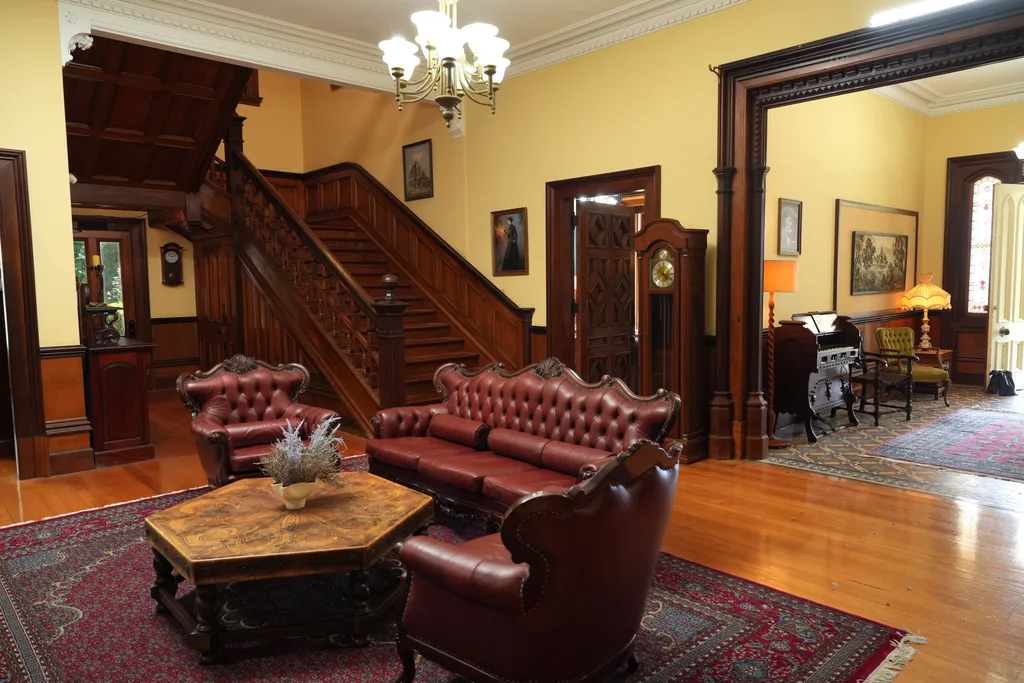 Wide entrance hall with timber staircase, antique furniture and polished hardwood floors.