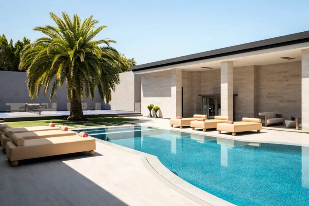 Resort-style swimming pool at Kylie Jenner’s Los Angeles home surrounded by sun lounges, palm trees and modern architecture.