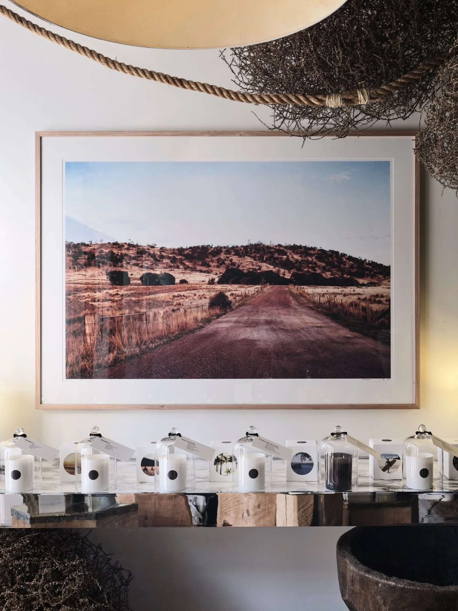 A photograph of the Australian outback above a side table with Raconteur candles, made in Australia.