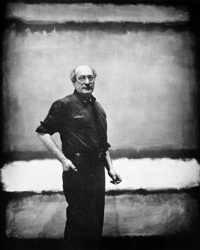 Mark Rothko, American abstract painter, pictured standing in front of one of his paintings