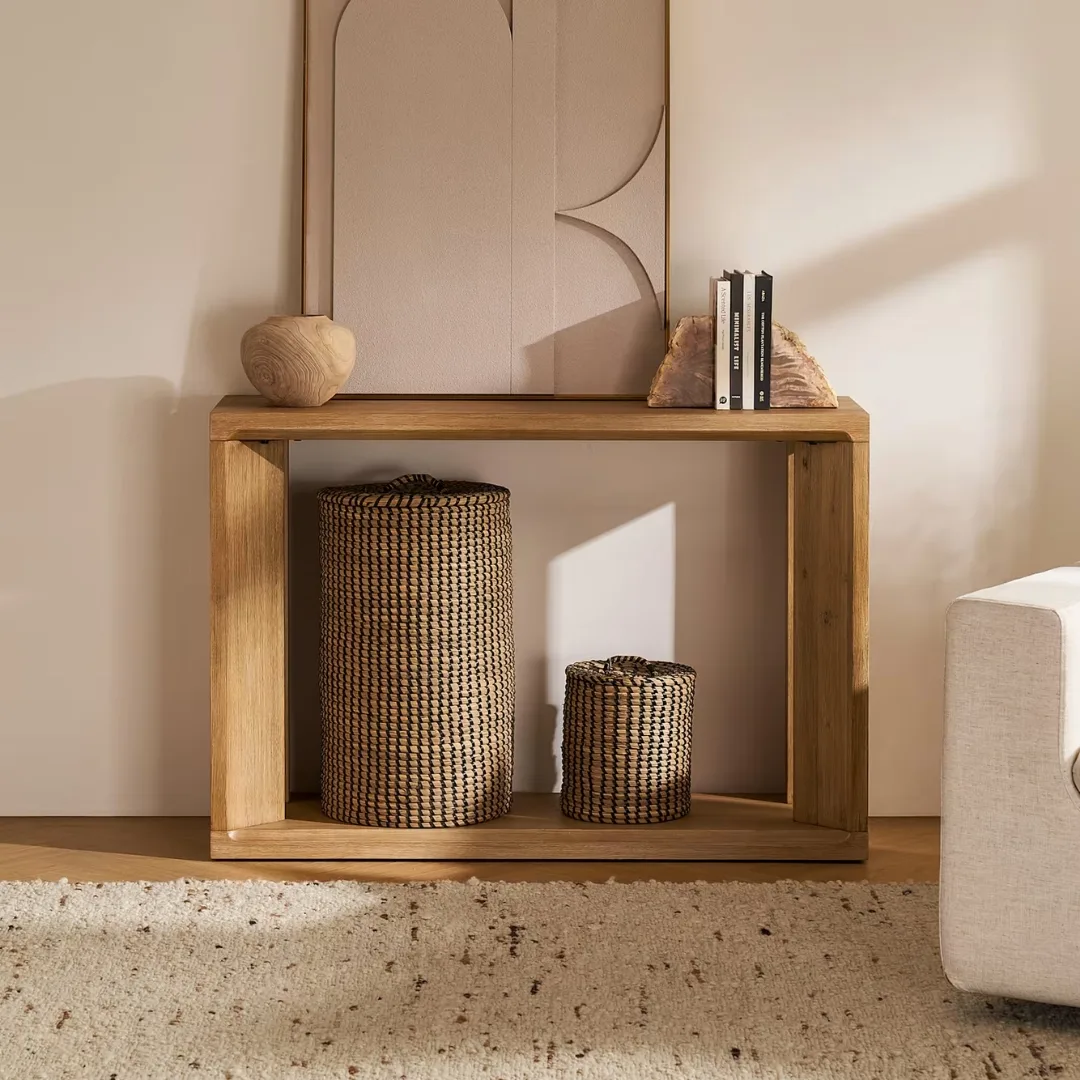 Boxy light timber console table with woven baskets beneath for shoe storage