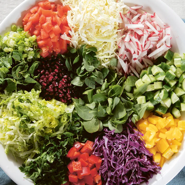 An aerial view of a large white bowl filled with colourful fattoush salad ingredients in different piles