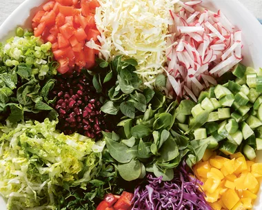 An aerial view of a large white bowl filled with colourful fattoush salad ingredients in different piles