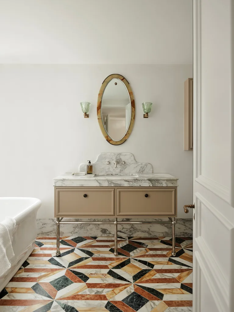 Elegant contemporary bathroom with marble floor, beige vanity, and oval mirror.