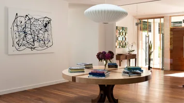 A modern living room with a large painting to the left that looks like it could have been done by Jackson Pollock