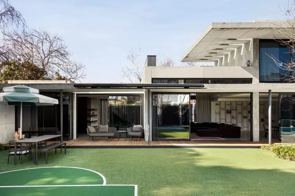 Outdoor entertaining area with lawn, private sports court and concrete exterior at the Brighton home.