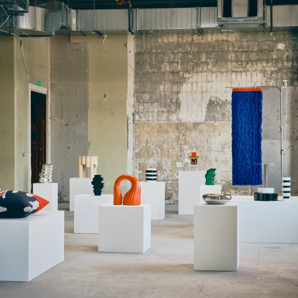 IKEA KONSTRUNDA sculptures, vessels, cushions and colourful textile artworks arranged on white plinths in an industrial gallery setting