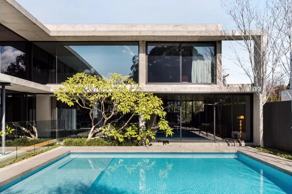 Swimming pool beside the concrete and glass exterior of the Bali Body founders' Brighton home.