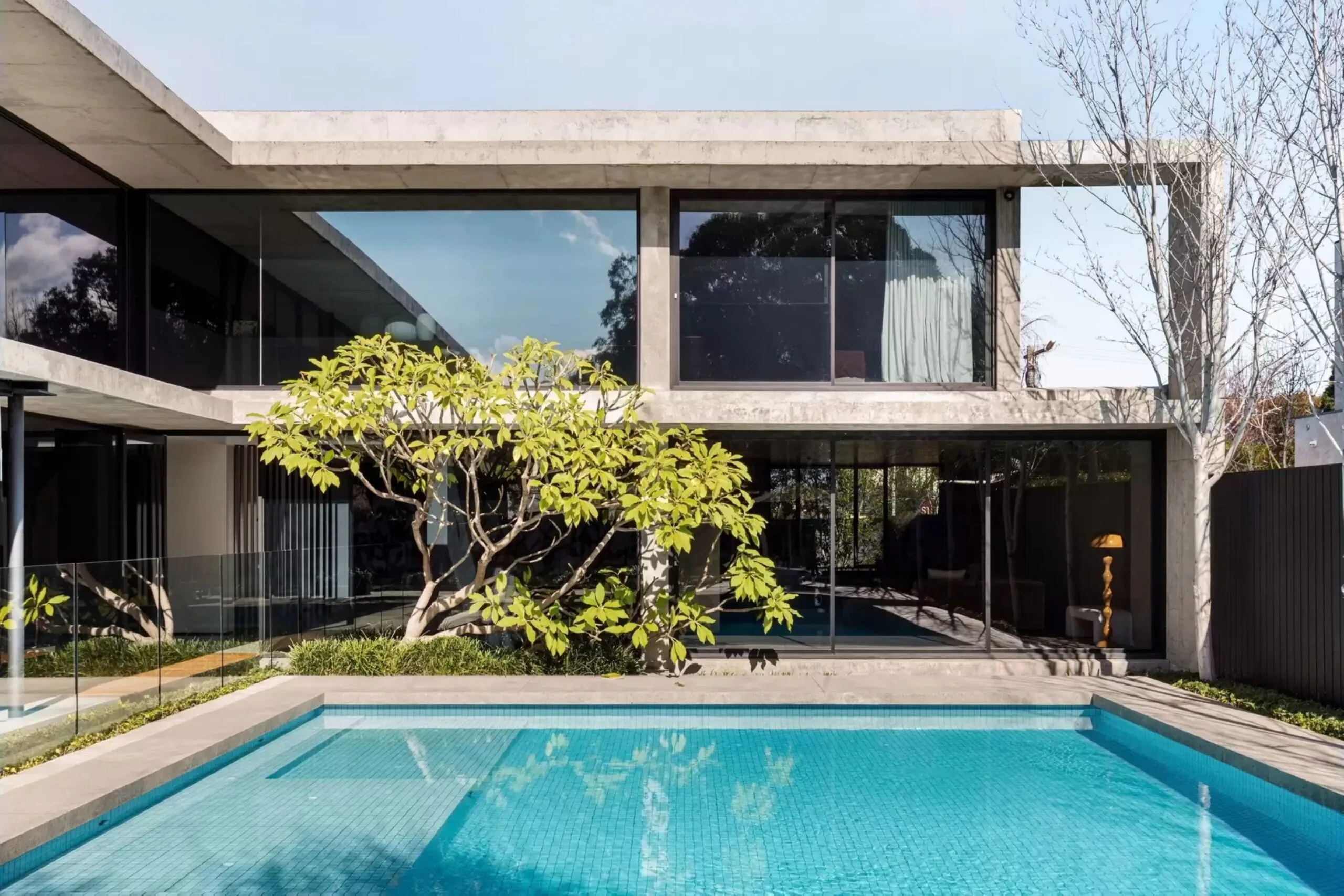 Swimming pool beside the concrete and glass exterior of the Bali Body founders' Brighton home.