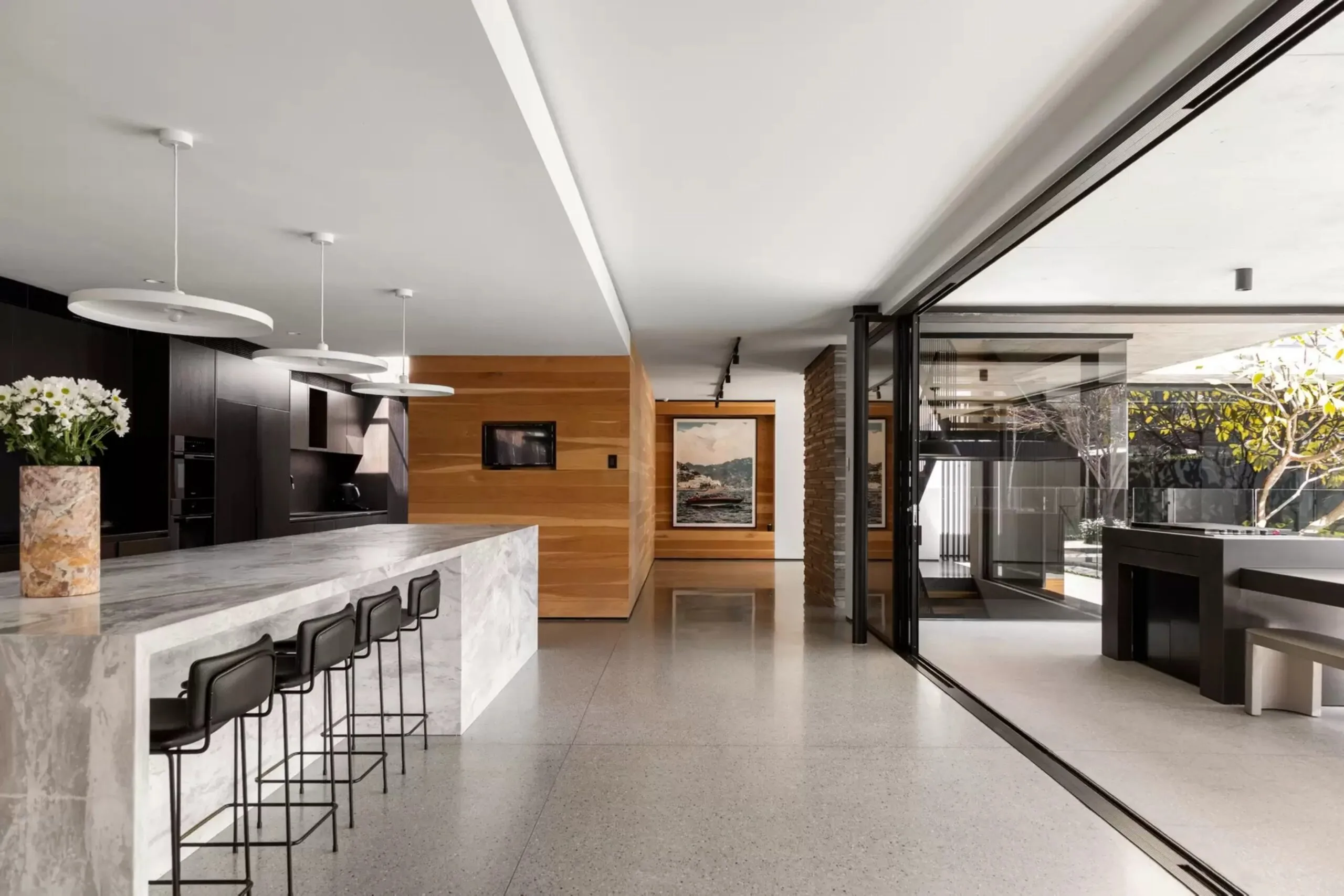Modern kitchen with a five-metre marble island, black cabinetry and polished concrete floors.