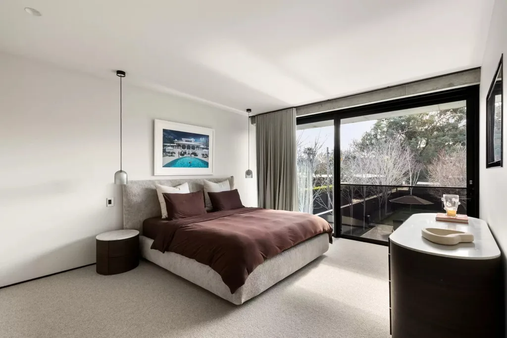 Bedroom with brown bedding, neutral carpet and large windows overlooking the garden.