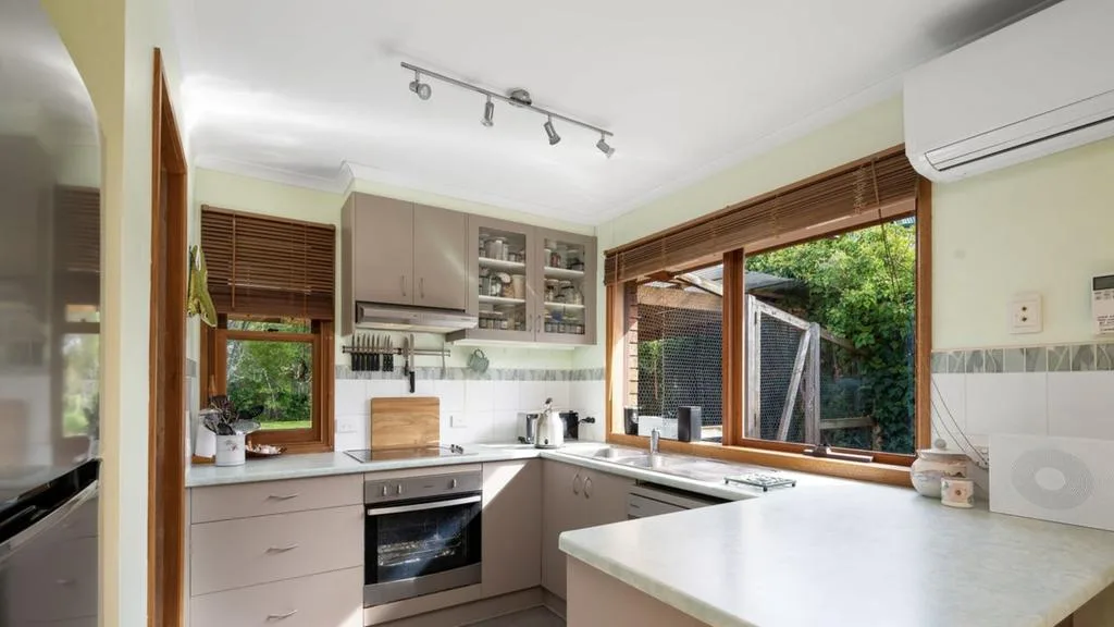 Existing kitchen with beige cabinetry, timber-framed windows and white tiled splashback at Emma and Ben&rsquo;s Mount Martha renovation project.