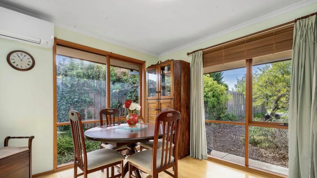 Dated dining room with timber-framed windows, wooden dining furniture and views of the garden at Emma and Ben&rsquo;s Mount Martha home.
