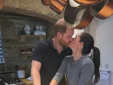 Meghan Markle and Prince Harry kiss beside a birthday cake in their rustic Montecito kitchen.