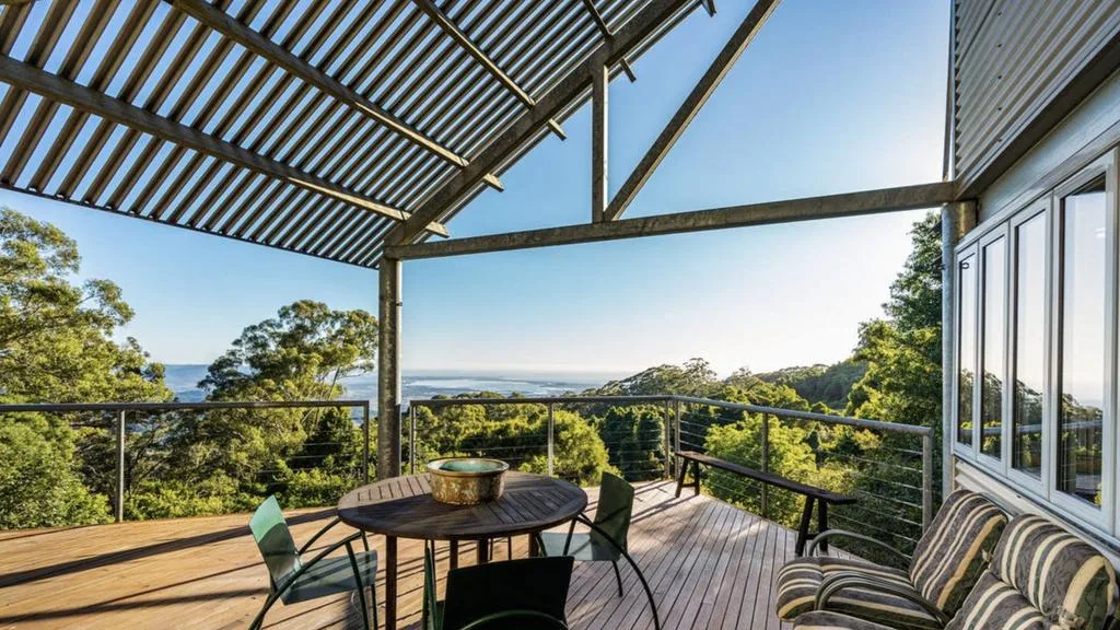 Covered timber deck overlooking rainforest and distant ocean views at Miriam Margolyes' Southern Highlands home.