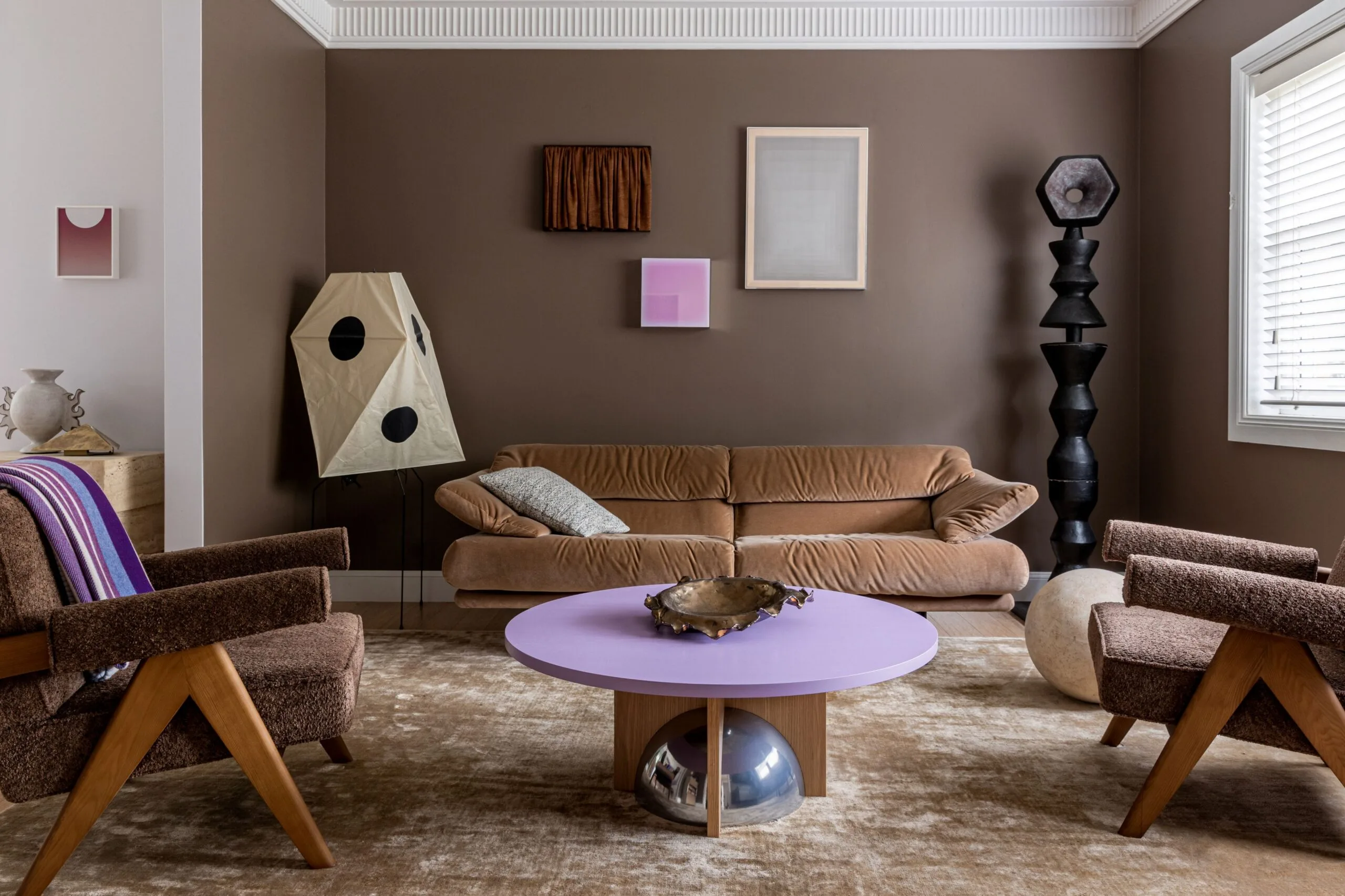 A living room with brown walls, a brown velvet sofa, and a purple coffee table
