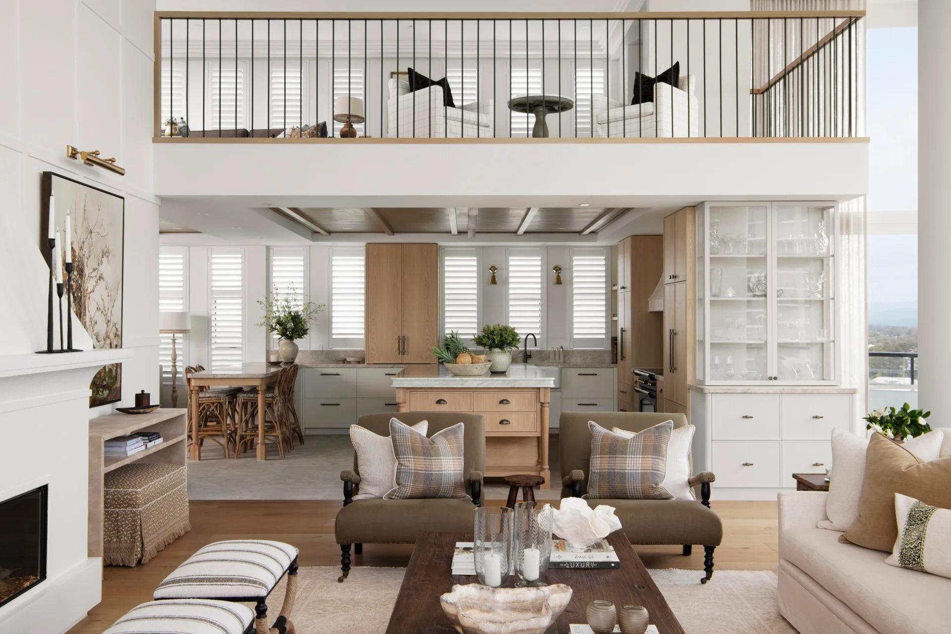Modern open-concept living room and kitchen with a mezzanine, neutral tones, and elegant furnishings.