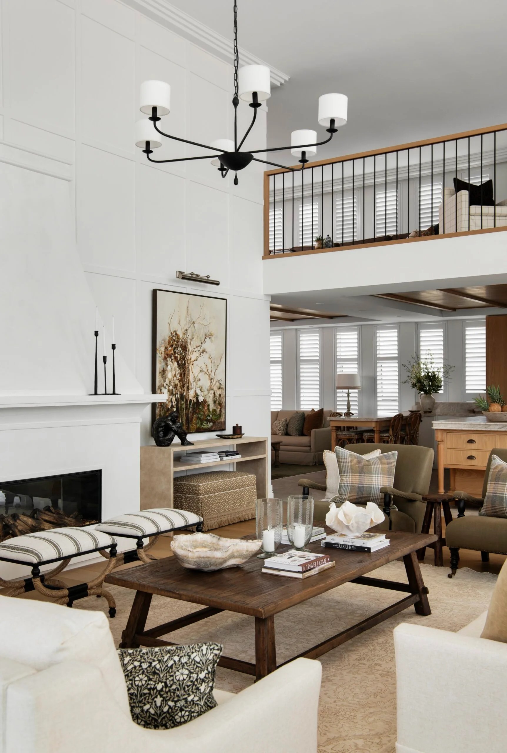 Stylish living room with a fireplace, large chandelier, and cozy seating, decorated in neutral tones and wood accents.