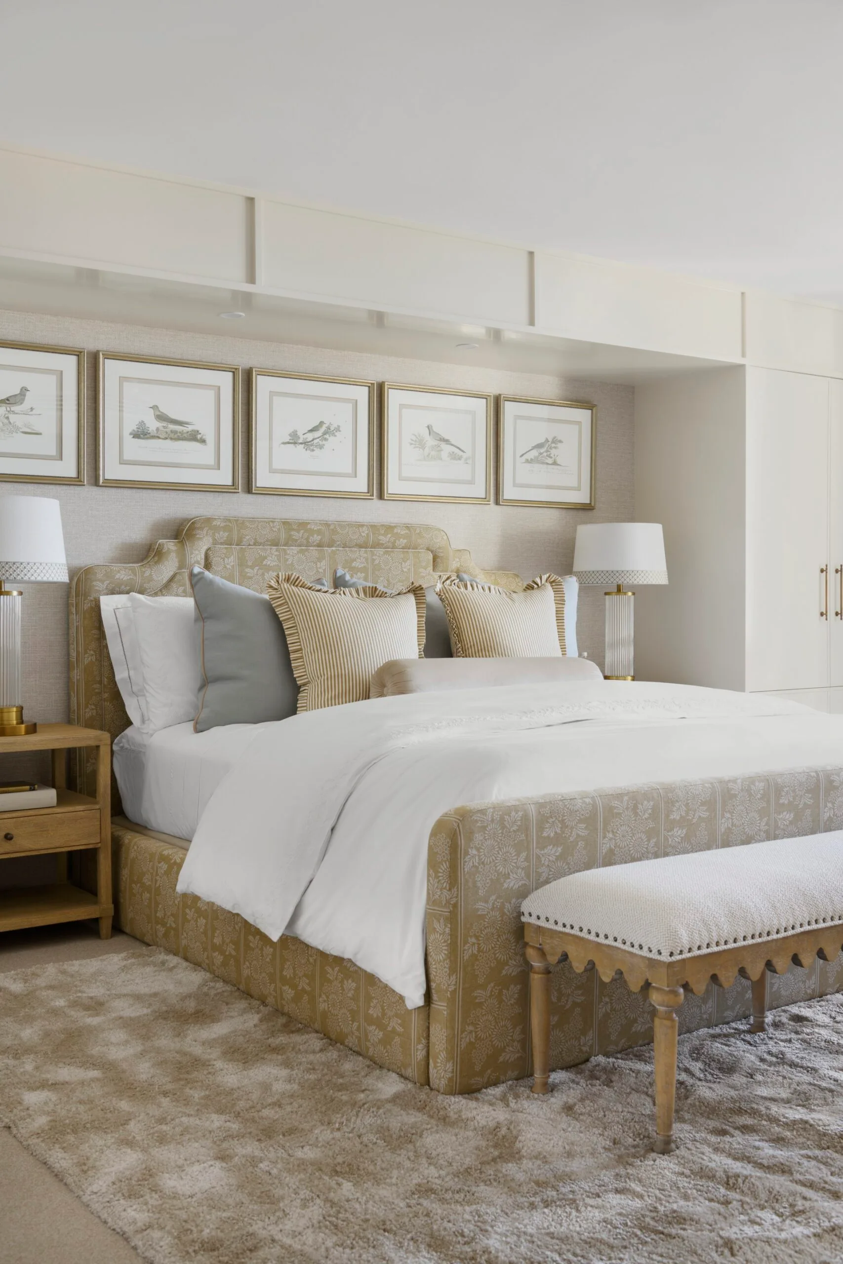 Elegant bedroom with a patterned bed, white bedding, framed bird art, and a cozy beige rug.