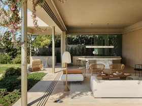 Open-plan living space. The large windows slide open to entirely open up the interior and exterior zones. Inside is an open-plan living and kitchen and on the facade of the building plants hang from the second storey down.