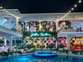 A beautifully lit villa at night with colorful decor, neon signs, and a pool in a tropical setting. This is the Love Island USA villa for 2026.