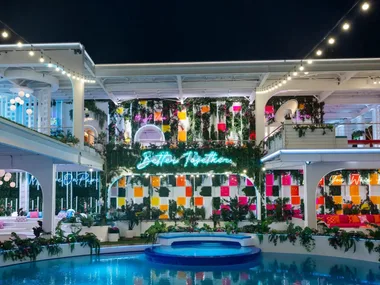 A beautifully lit villa at night with colorful decor, neon signs, and a pool in a tropical setting. This is the Love Island USA villa for 2026.