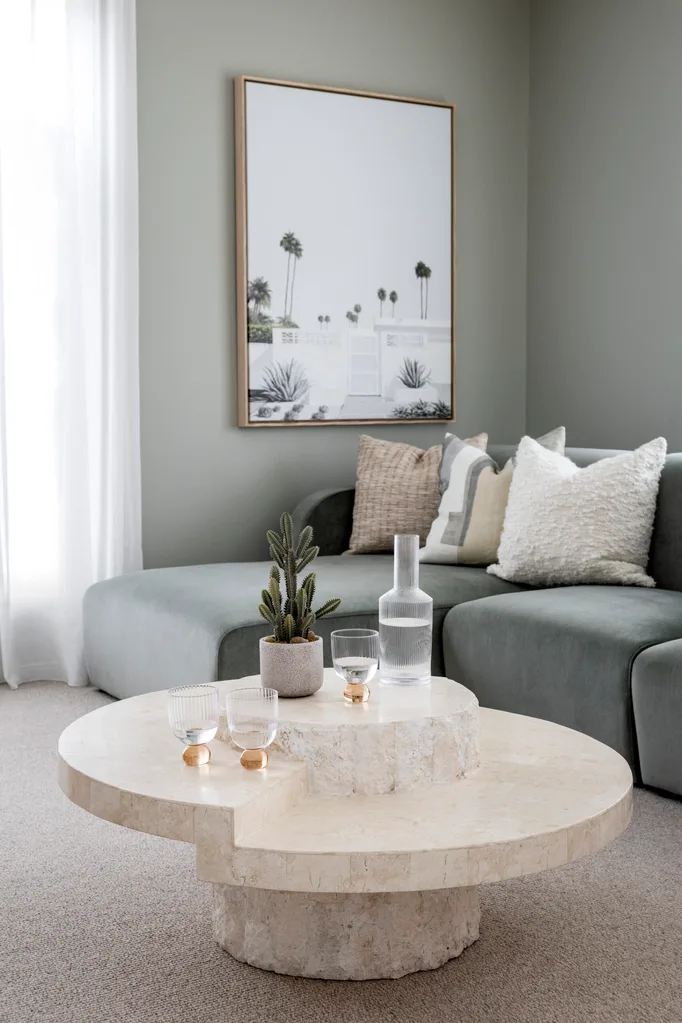 Contemporary living room in Palm Springs style with seaglass blue walls a velvet soft blue sofa and round solid stone coffee table