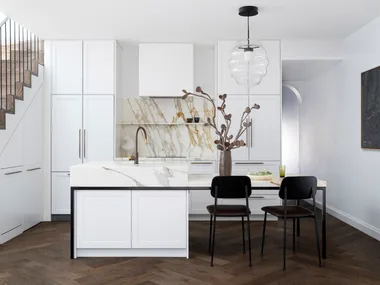 A modern kitchen with white cabinets, a marble island, dark wood flooring, pendant light, and two chairs.