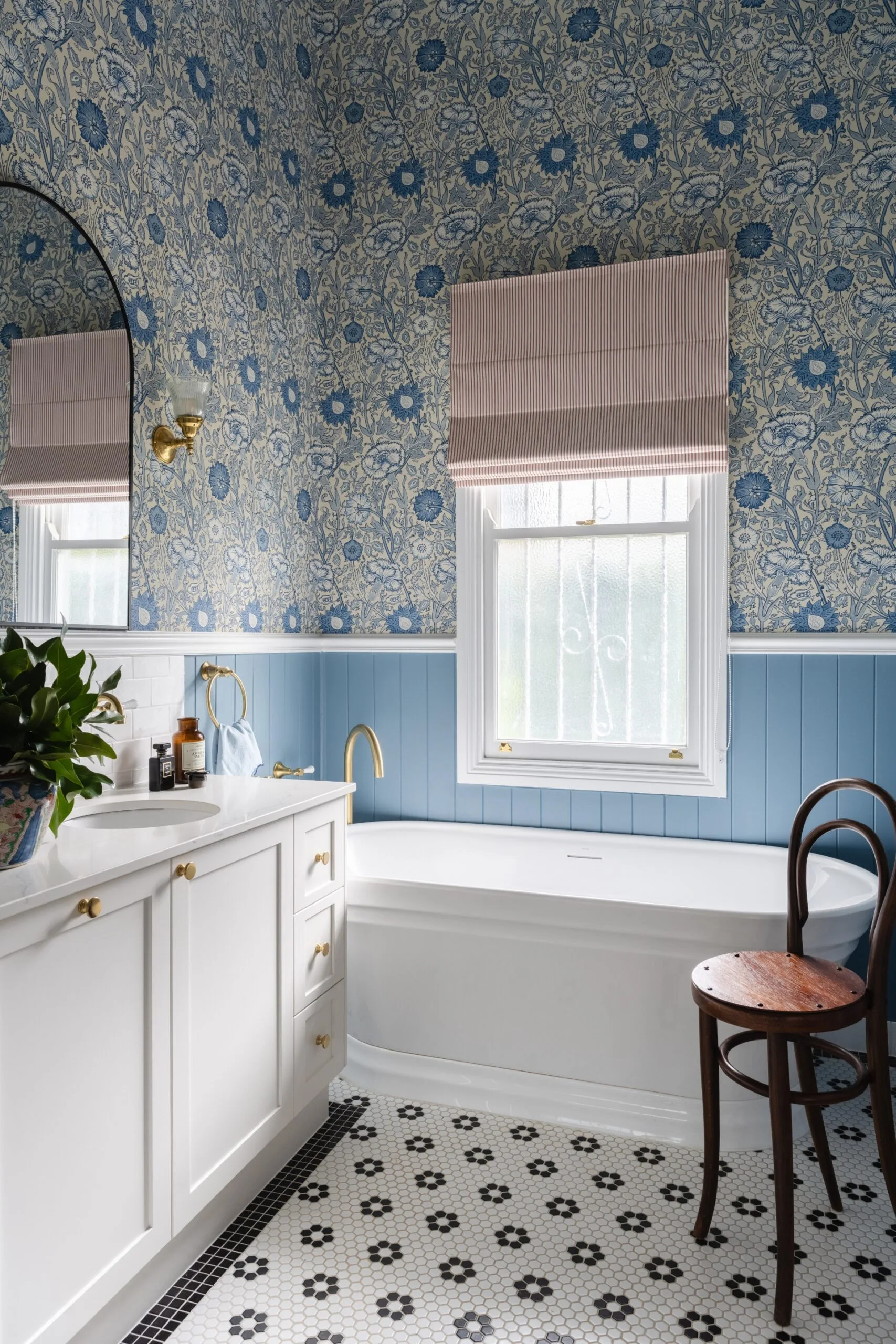 Elegant bathroom with blue floral wallpaper, striped blinds, white bathtub, and patterned floor tiles.