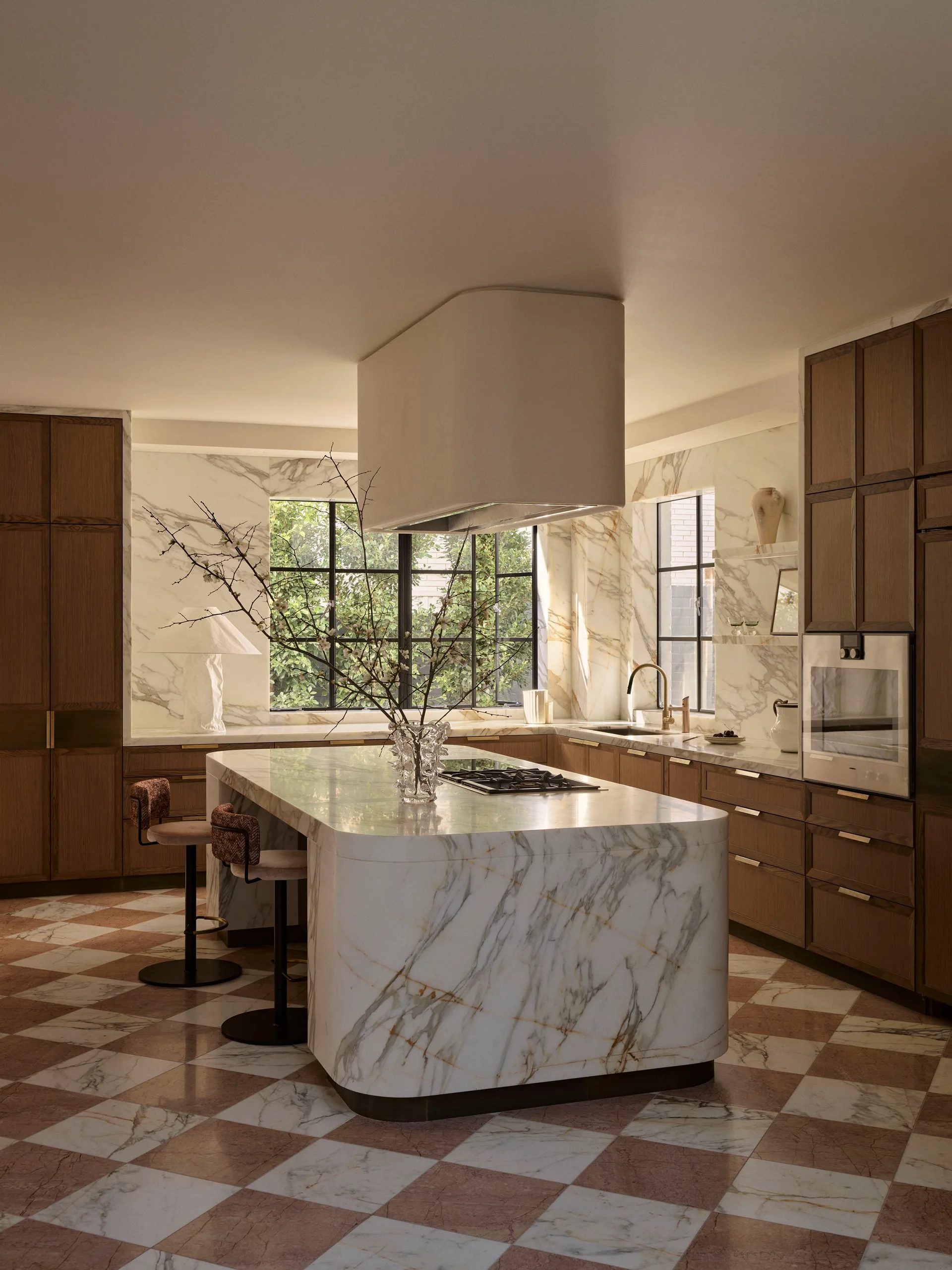 Sleek kitchen with marble island, wooden cabinets, large windows, and checkered floor.