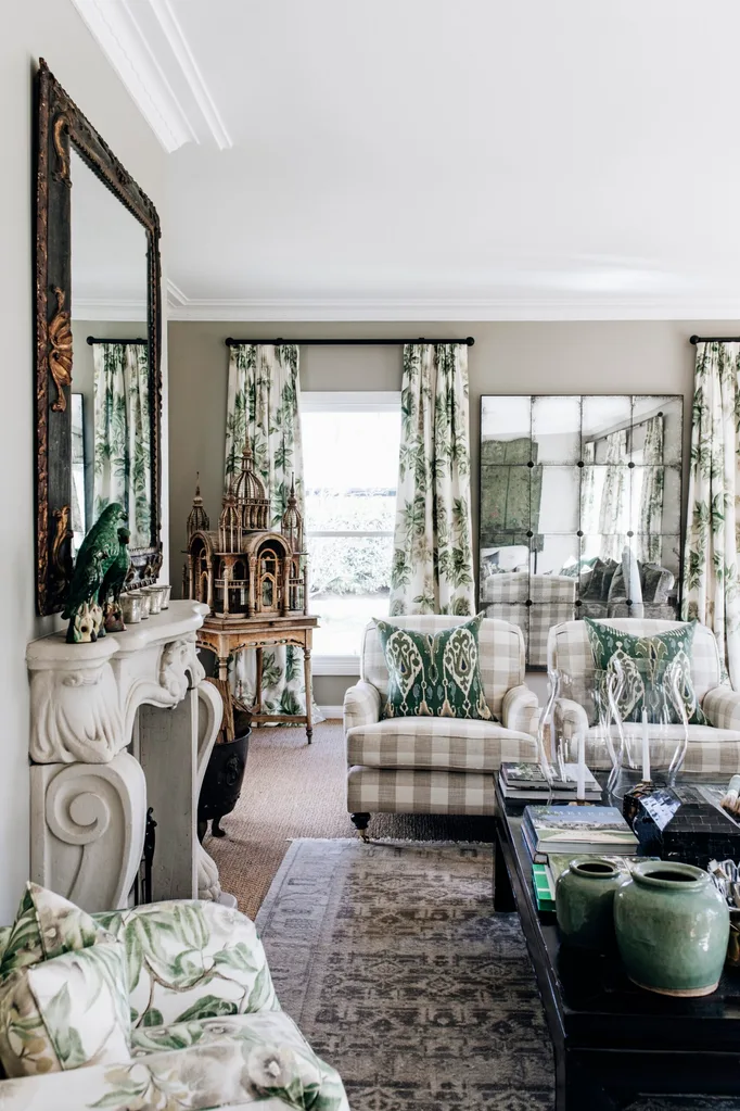Elegant living room with patterned furniture, green accents, large mirror, and decorative bird sculpture on a mantle.