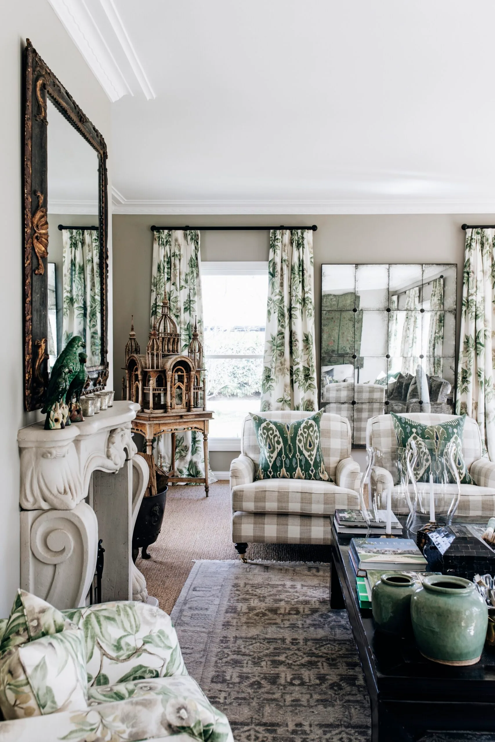 Elegant living room with patterned furniture, green accents, large mirror, and decorative bird sculpture on a mantle.