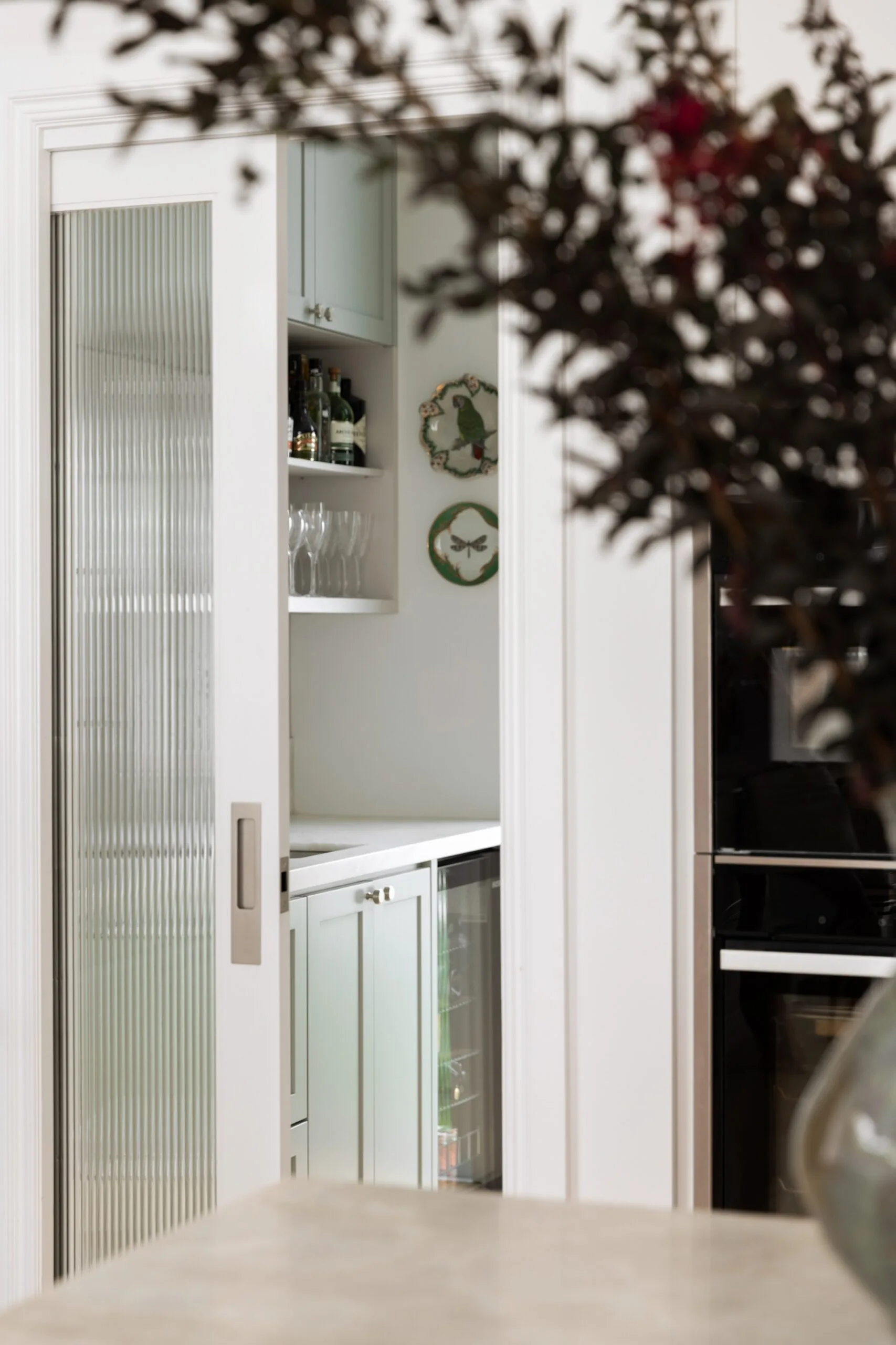 Sliding door reveals bar area with liquor bottles, glasses, and decorative plates.