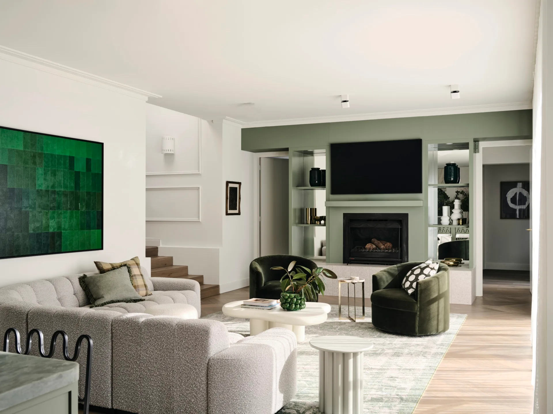 Bright living room with green accents, plush sofas, plant decor, and a fireplace beneath a wall-mounted TV.