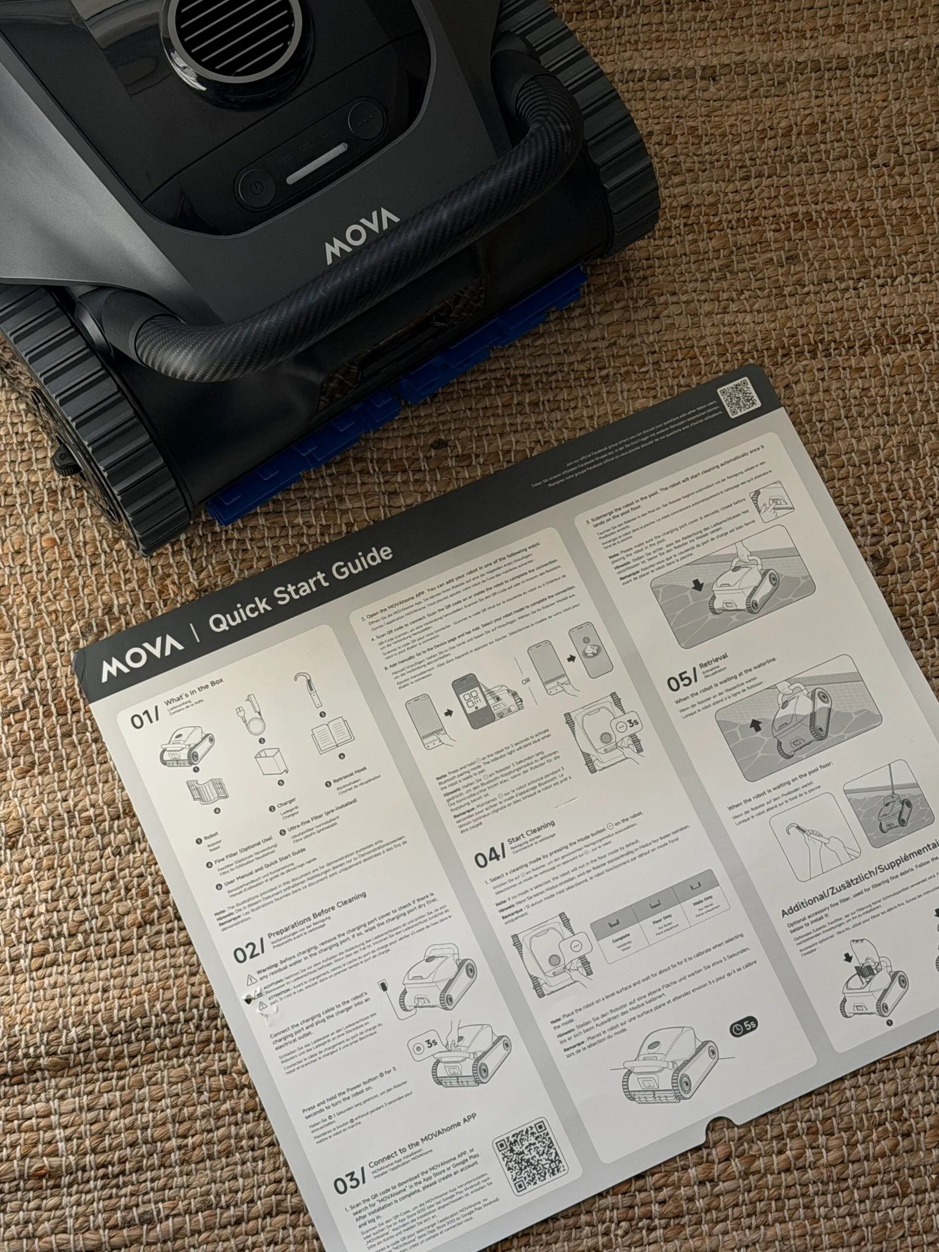 MOVA robotic vacuum with quick start guide on a woven mat surface.