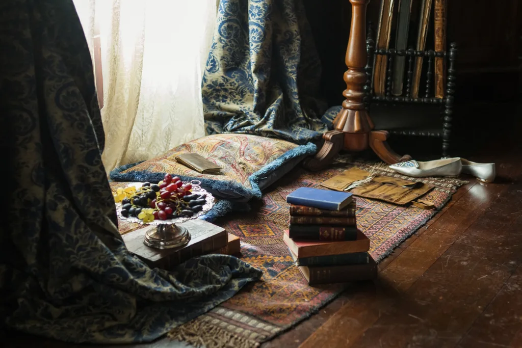 a still from my brilliant career with a bowl of grapes and a stack of books between luxurious curtains