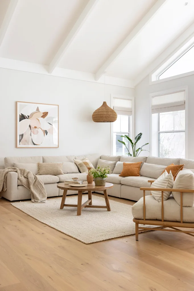 Stylish living room with a light gray sectional, wooden coffee table, neutral decor, and abstract wall art.