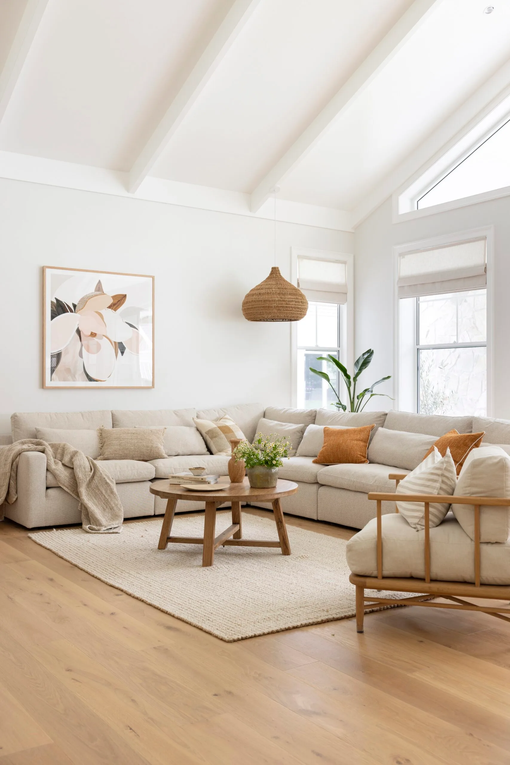 Stylish living room with a light gray sectional, wooden coffee table, neutral decor, and abstract wall art.