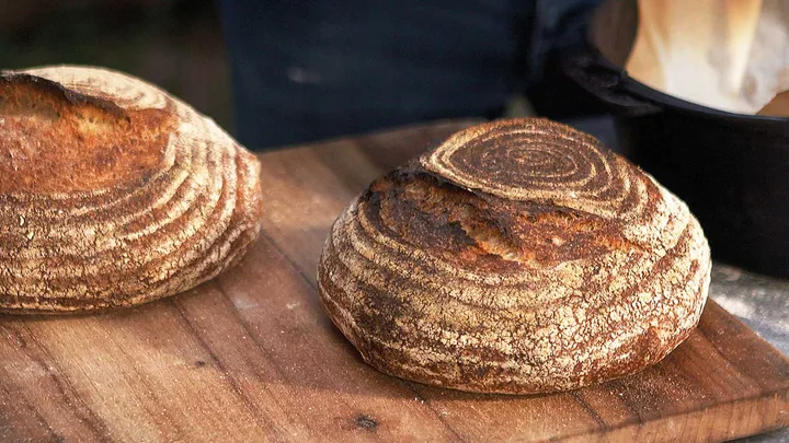 Two round loaves of wood-fired sourdough bread on a rustic wooden chopping board