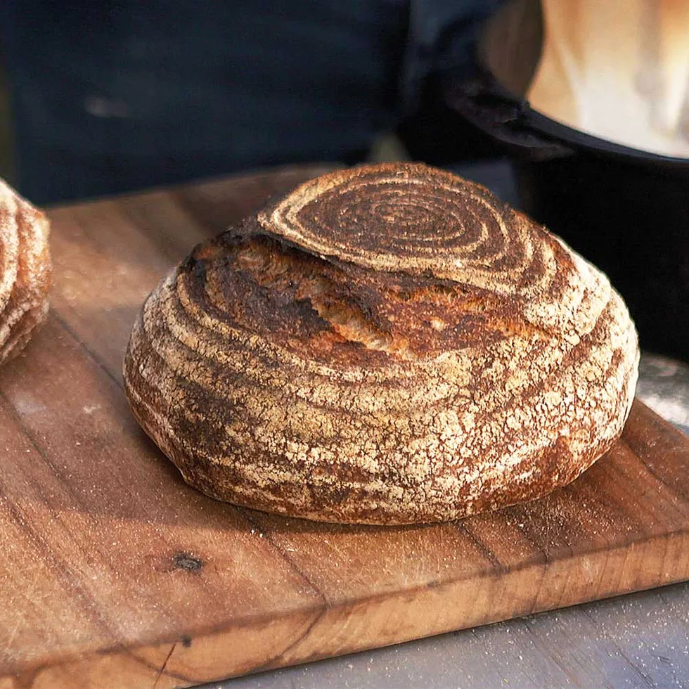 Two round loaves of wood-fired sourdough bread on a rustic wooden chopping board