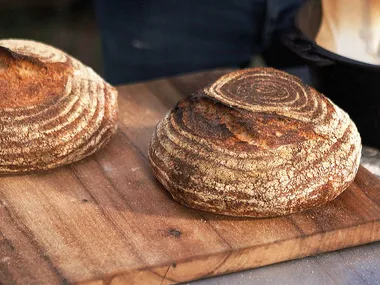 Two round loaves of wood-fired sourdough bread on a rustic wooden chopping board