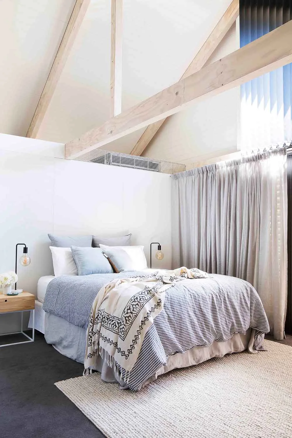 Pale timber beams and soaring double-height windows steal the show in Rachael and Alex’s bedroom