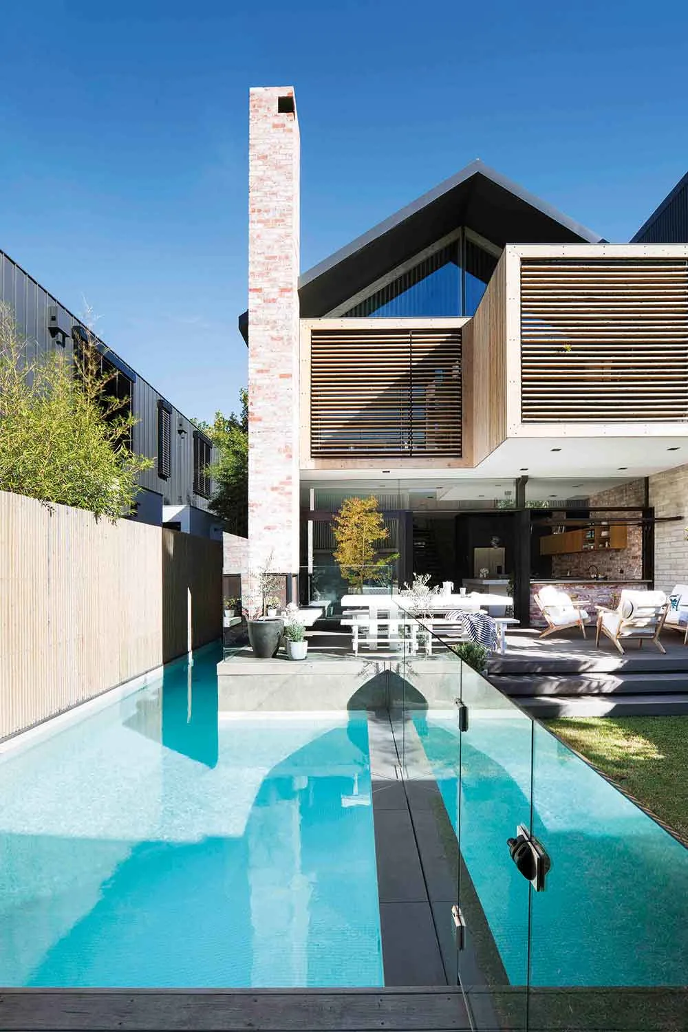 From the back, a towering chimney of recycled brick rises from a wood-burning outdoor fire, while cypress timber panelling upstairs adds wonderful texture and warmth.