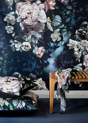 Floral wall mural with a floral throw on a wooden bench and floral cushions on the floor.