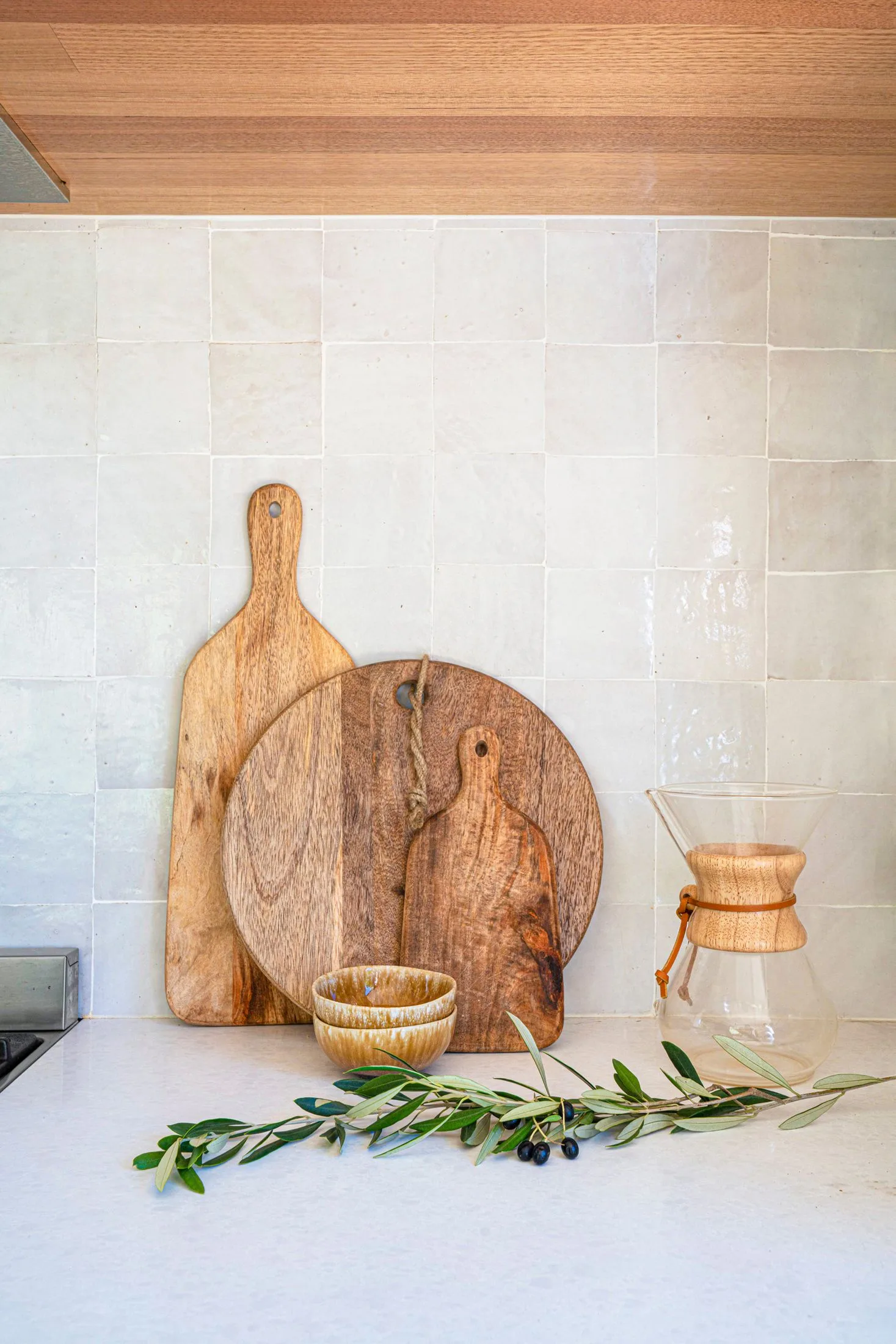 Wooden cutting boards on neutral tile splashback